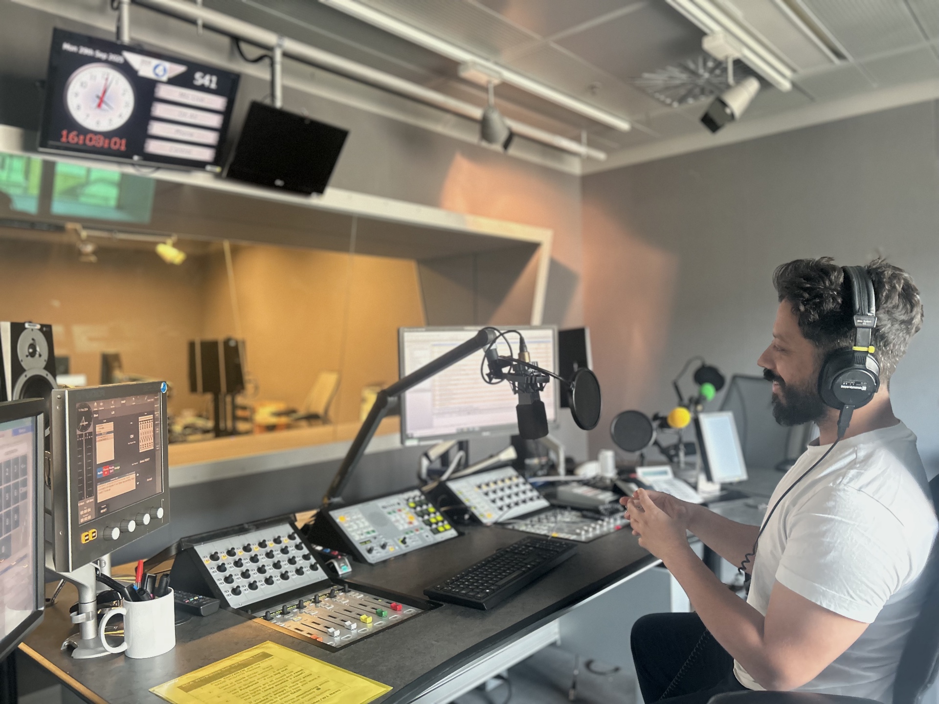 Craig Langran producing in a radio studio, wearing headphones at a broadcast mixing desk.